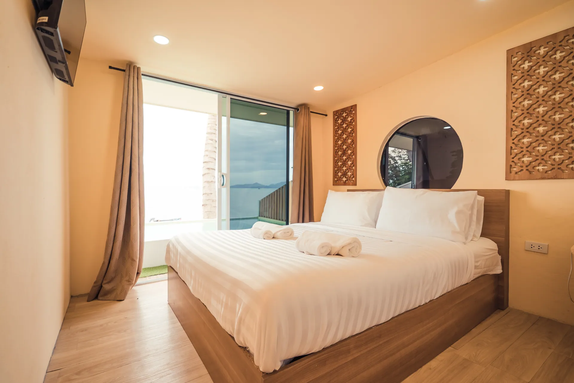 Sea-view bedroom with a double bed, a round porthole window and sliding glass doors opening to the pool terrace