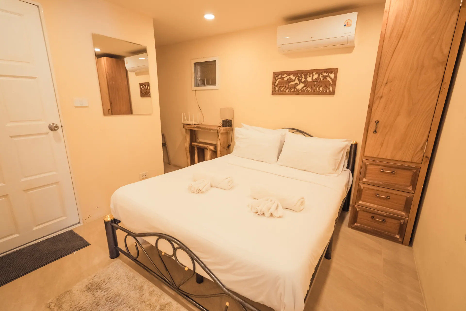 Double bedroom with a metal-framed bed, a tall timber wardrobe and a carved wall panel