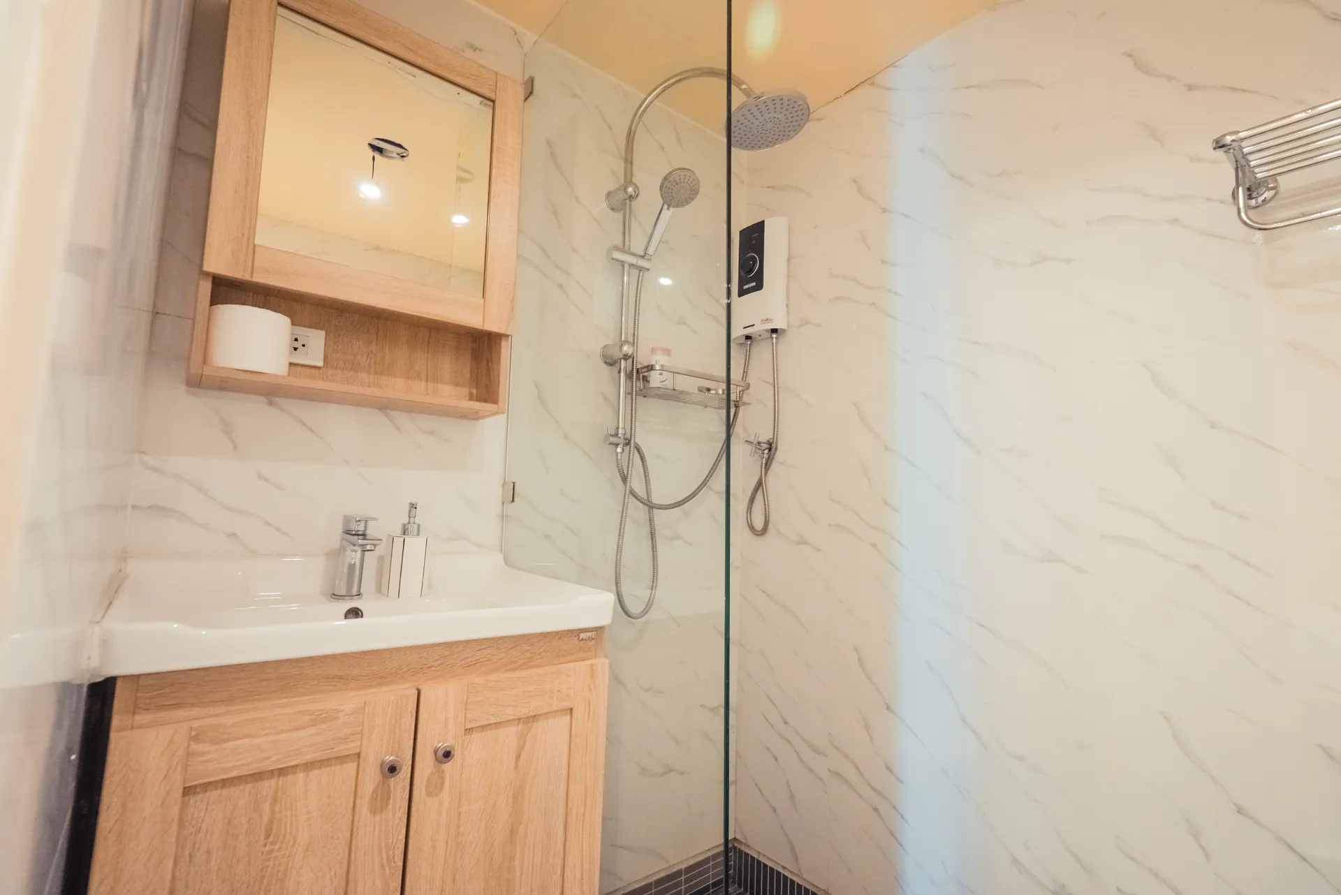 Bathroom with marble-effect walls, a timber vanity, a mirrored cabinet and a glass-screened rain shower