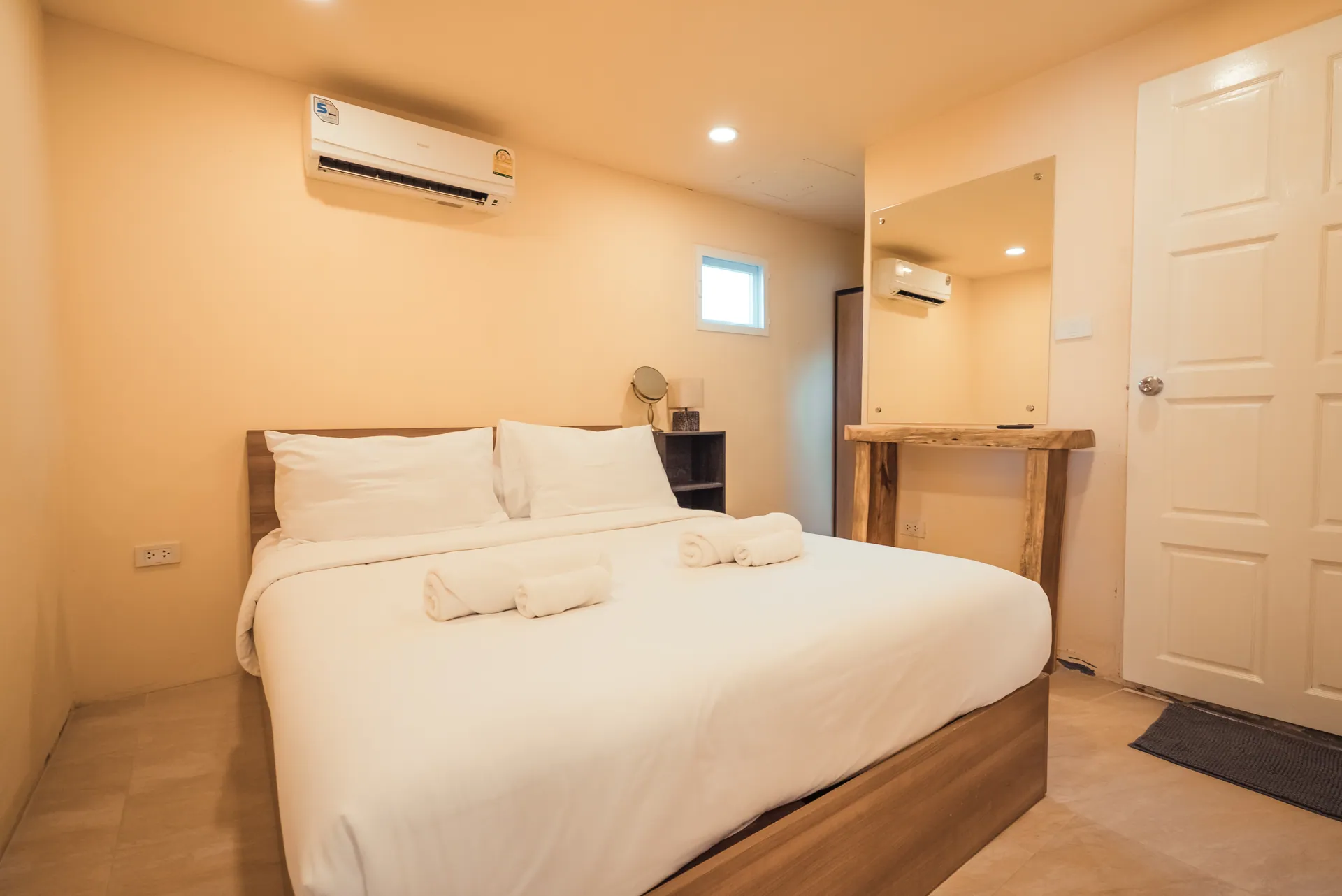 Double bedroom with white linen, a timber dressing table and air conditioning