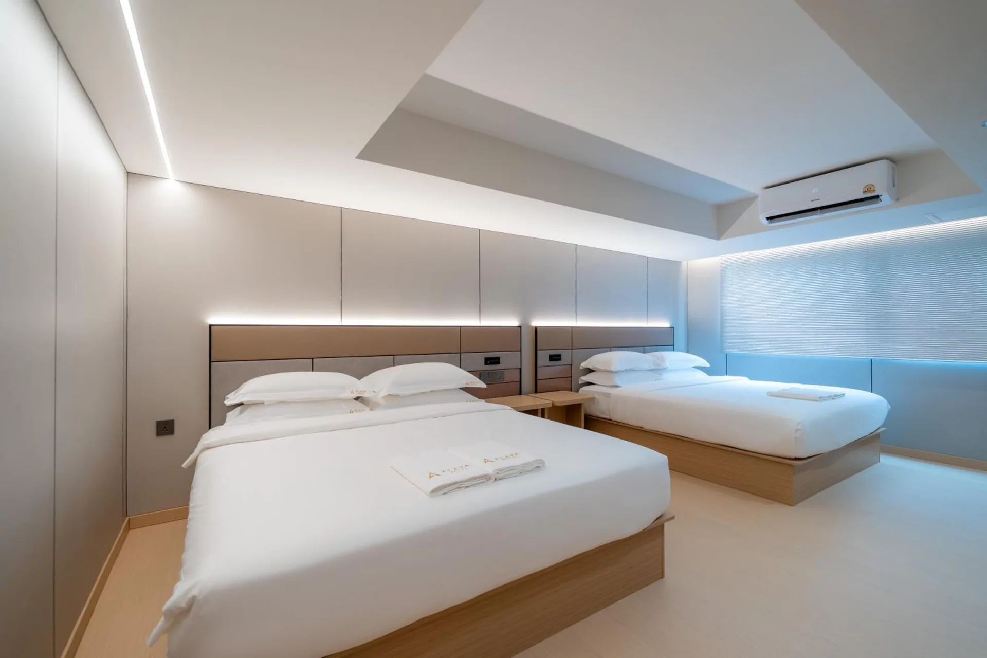 Two queen beds side by side beneath a lit headboard panel