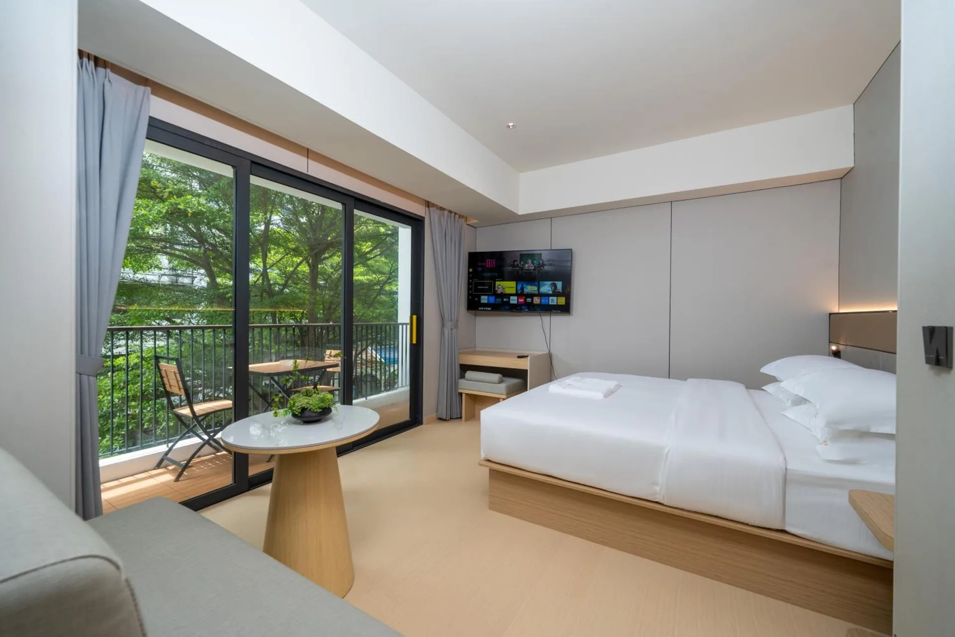 Bedroom with a king bed and a round table by glass doors to the balcony