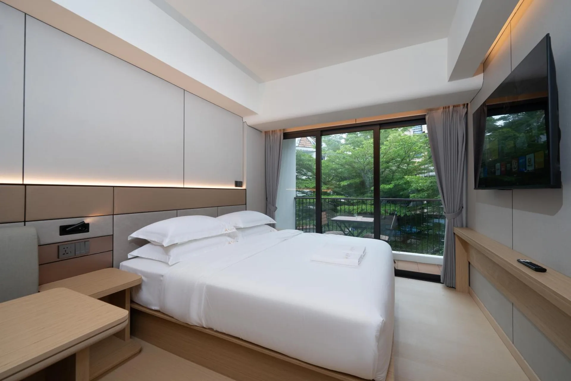 King bed facing glass doors to the balcony and the street trees